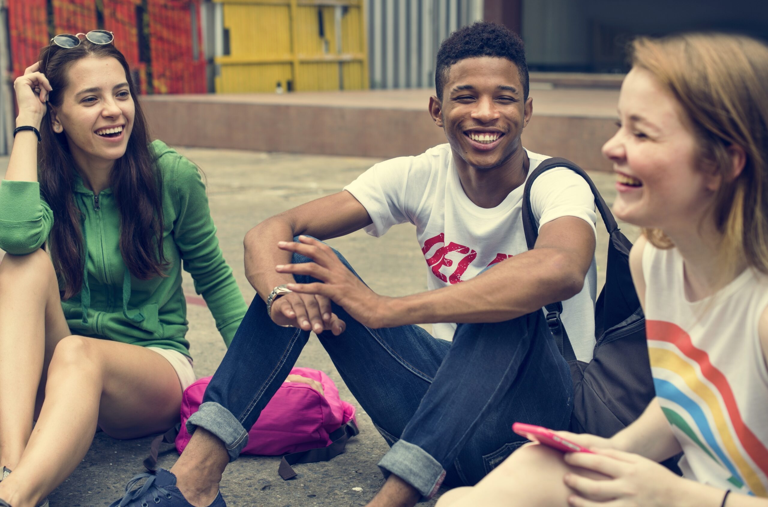 Group of happy teenagers laughing sitting in group on floor